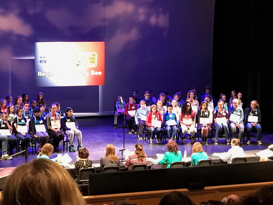 kids sitting on a stage with a screen behind them