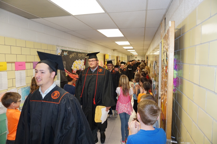 graduates walking past small children