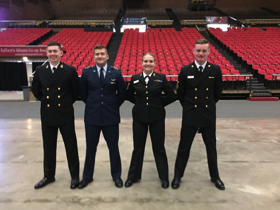 four uniformed individuals standing at ease