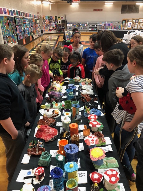 students crowding around a table full of artwork