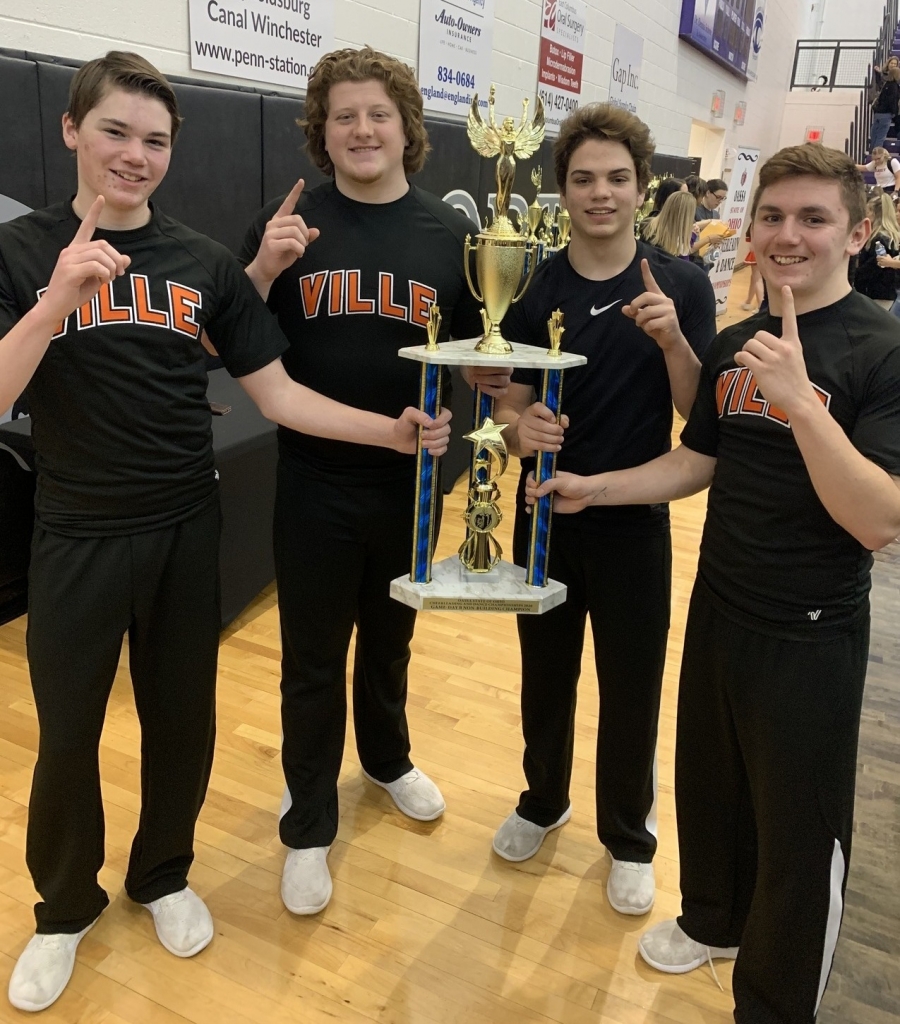 four male cheerleaders holding a trophy