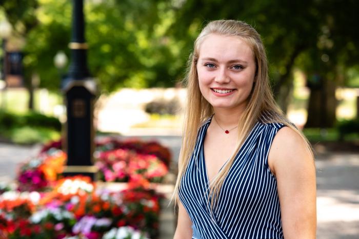 girl posing with some flowers in background