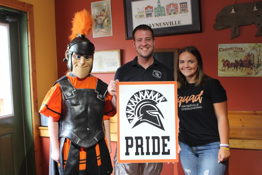 spartan mascot and three people holding a sign