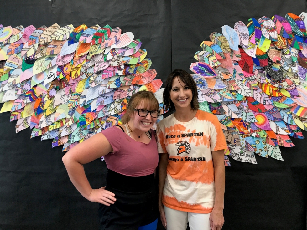 two women in front of decorative wall wings