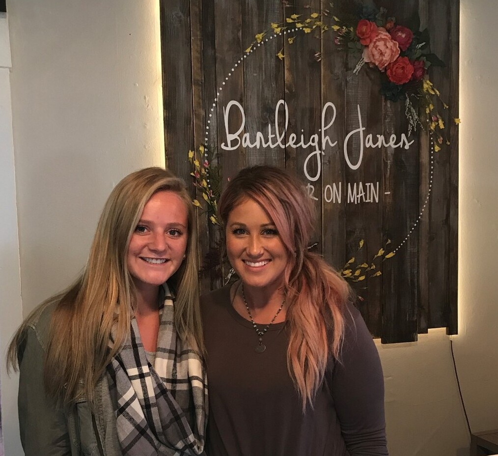 two girls standing in front of a sign